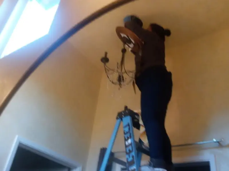 Electrician installing a chandelier in a Weiser residence